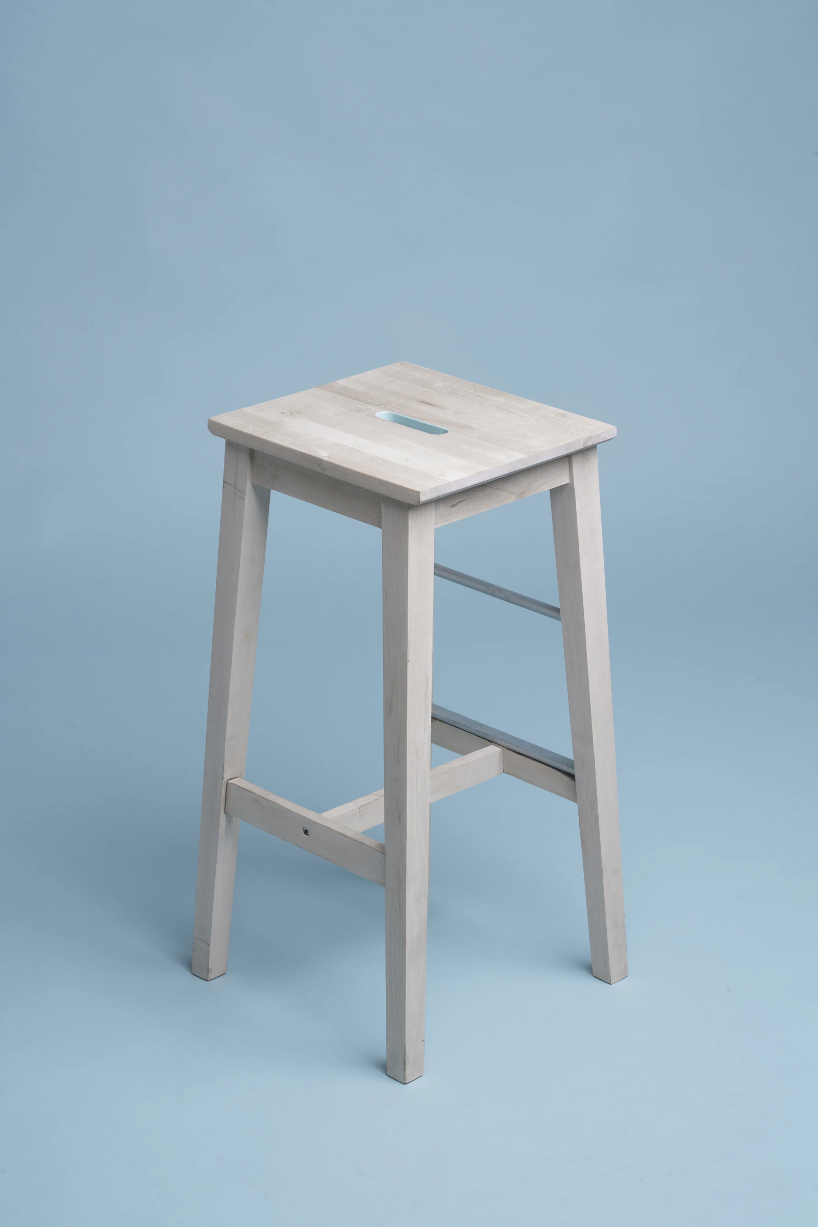 Light wooden stool against a blue backdrop