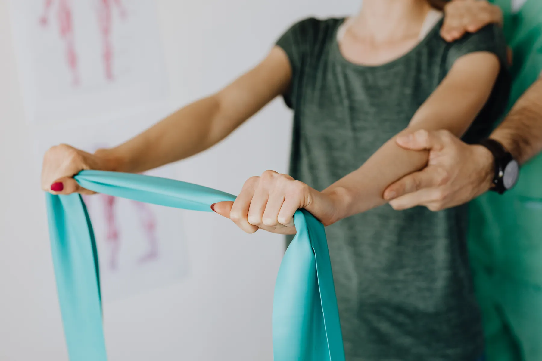 Person exercising with a resistance band while another person guides the arm
