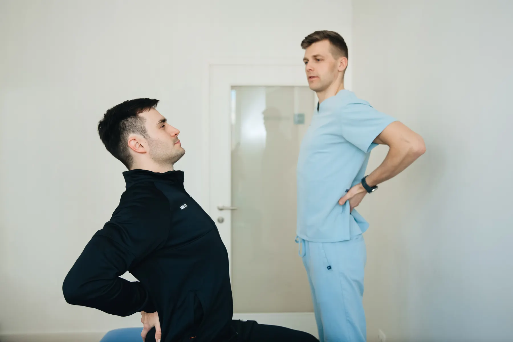 Provider guiding a patient through a back movement in a rehabilitation room
