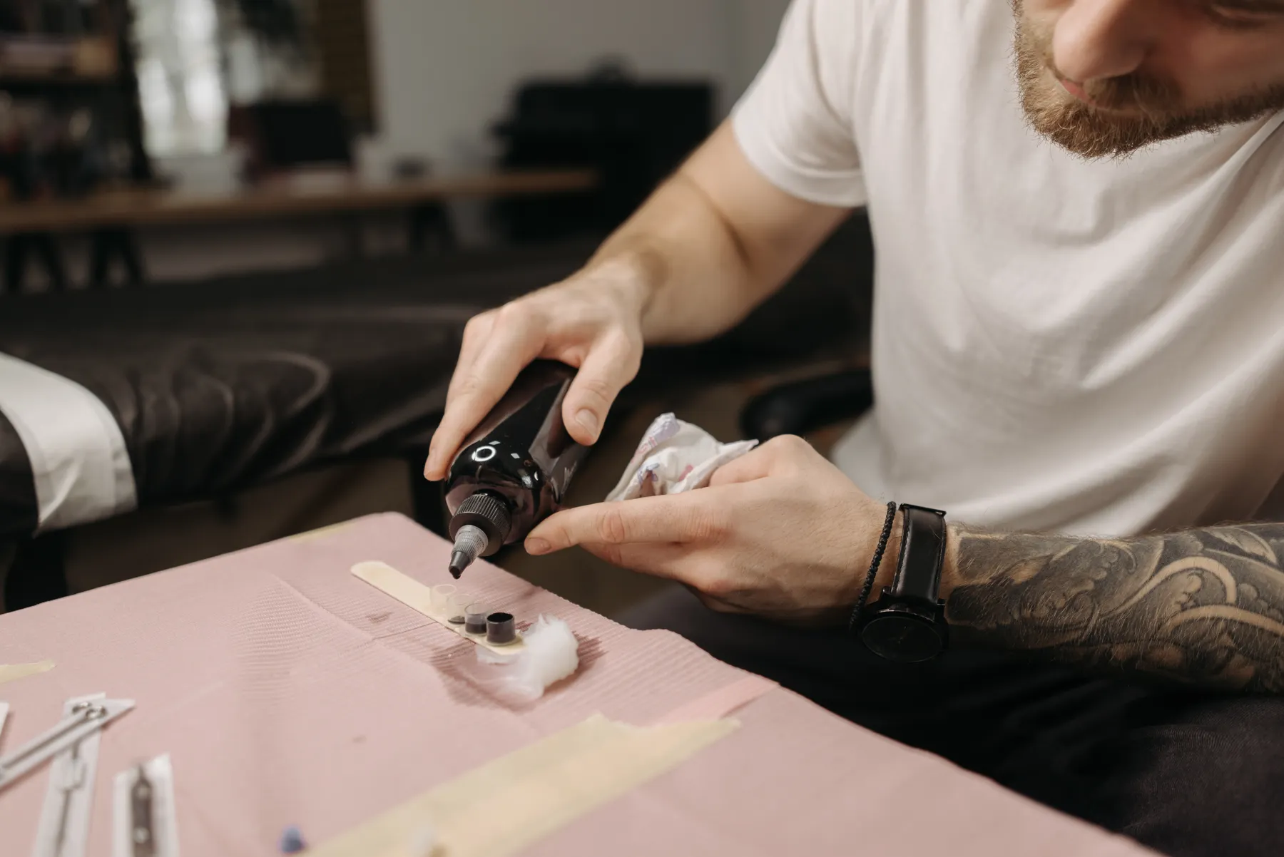 Tattoo artist preparing small ink cups on a work surface