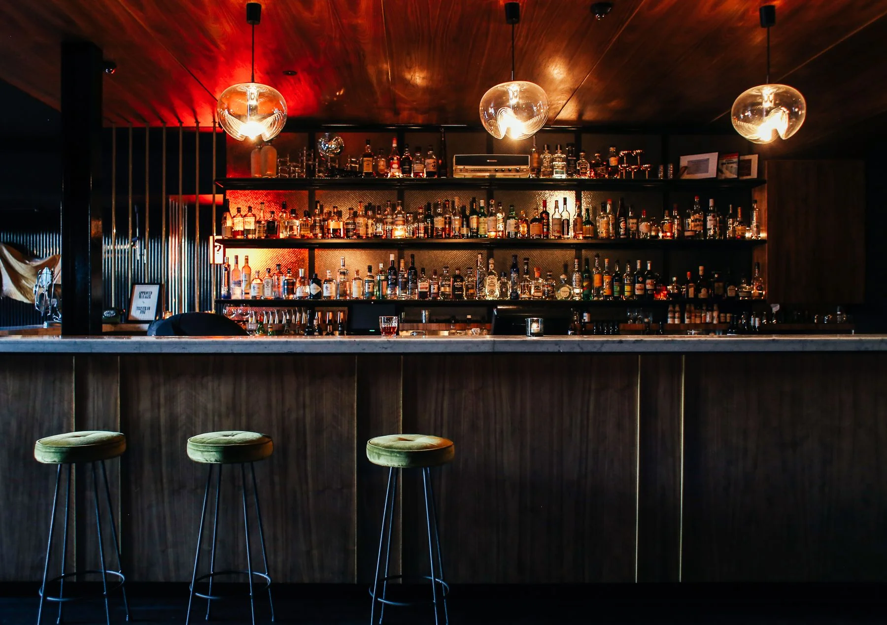 A wood-lined bar with globe lights and stools
