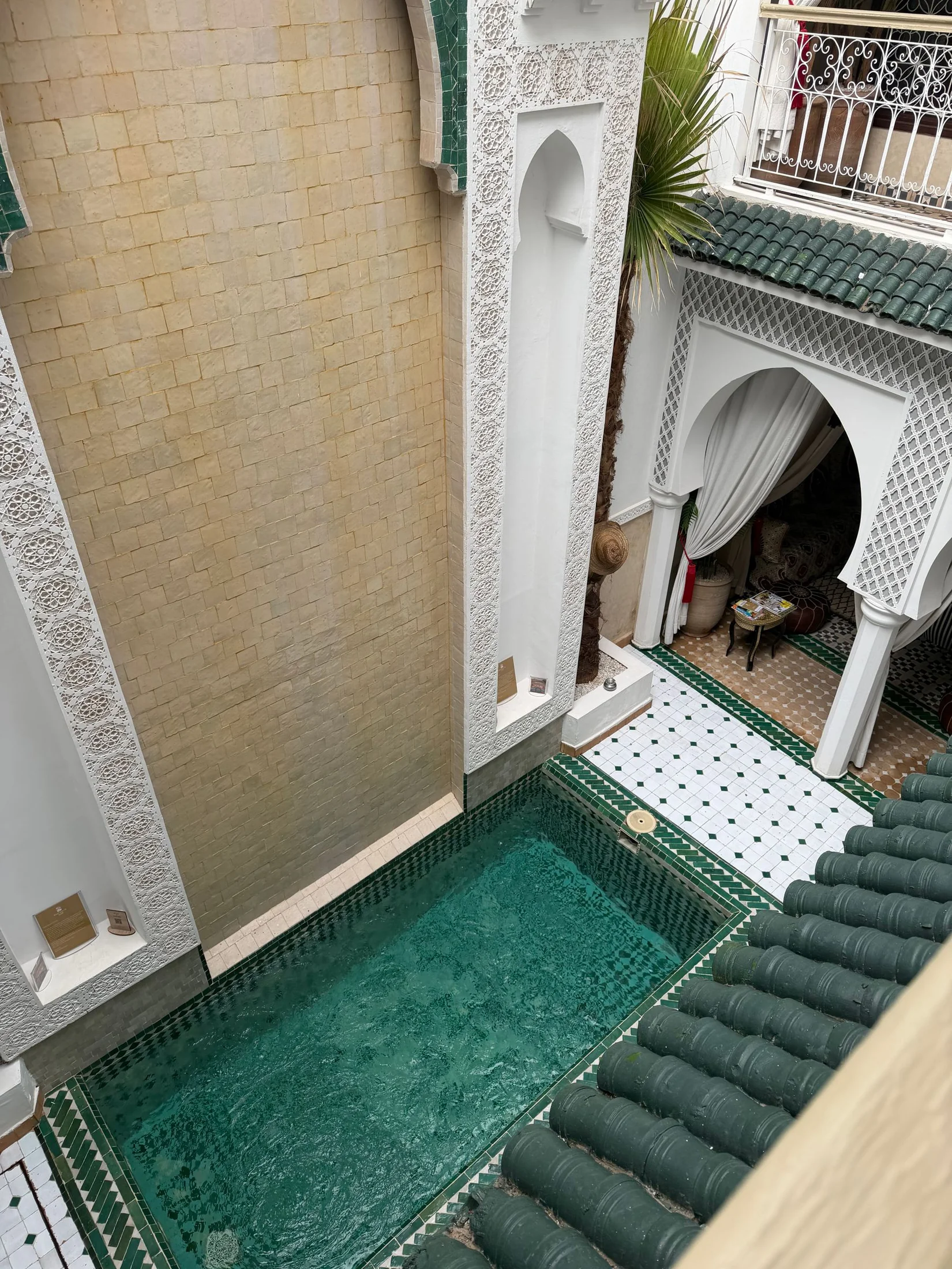 An arched courtyard with patterned tiles and a turquoise pool