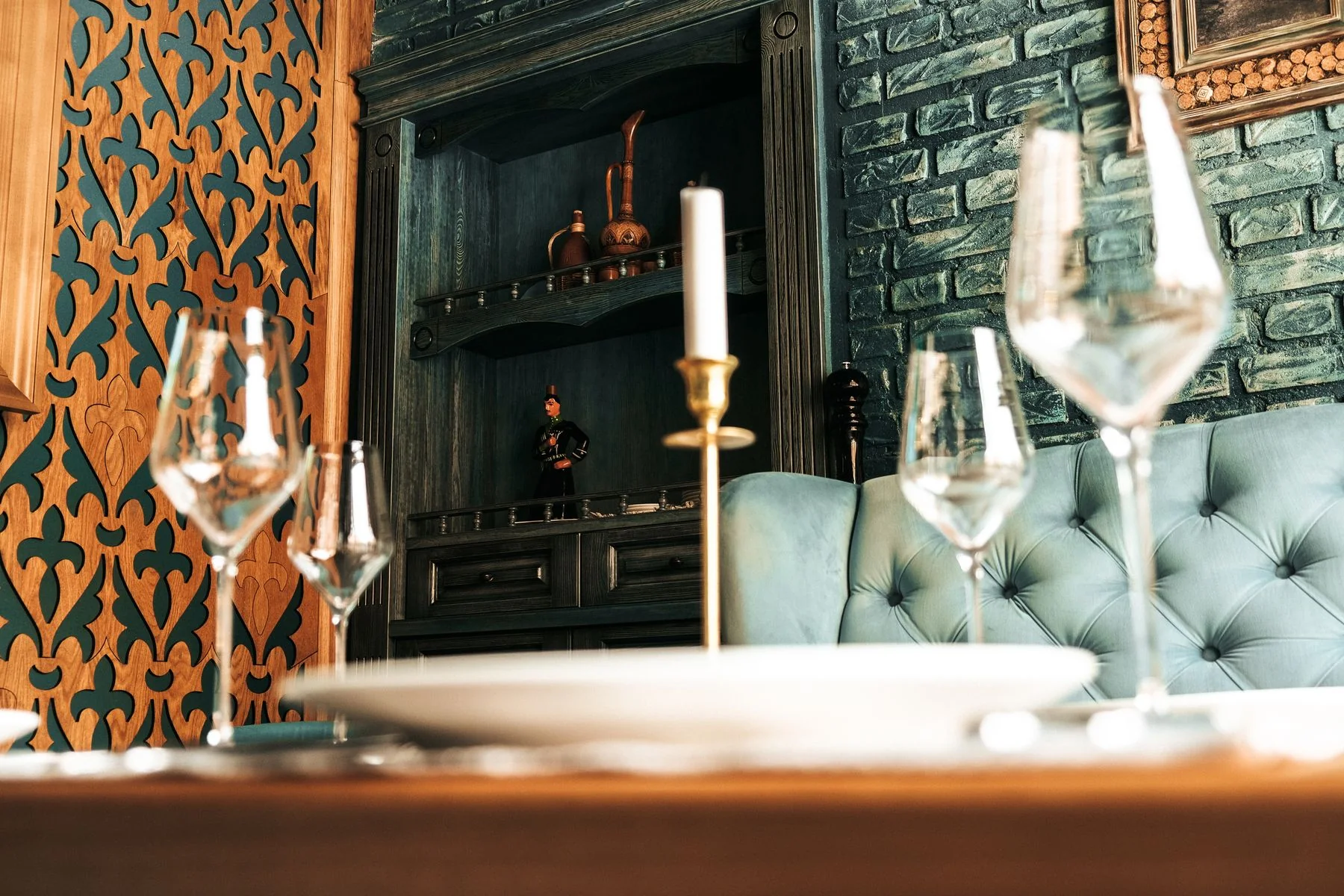 Glassware and a candle beside teal restaurant seating