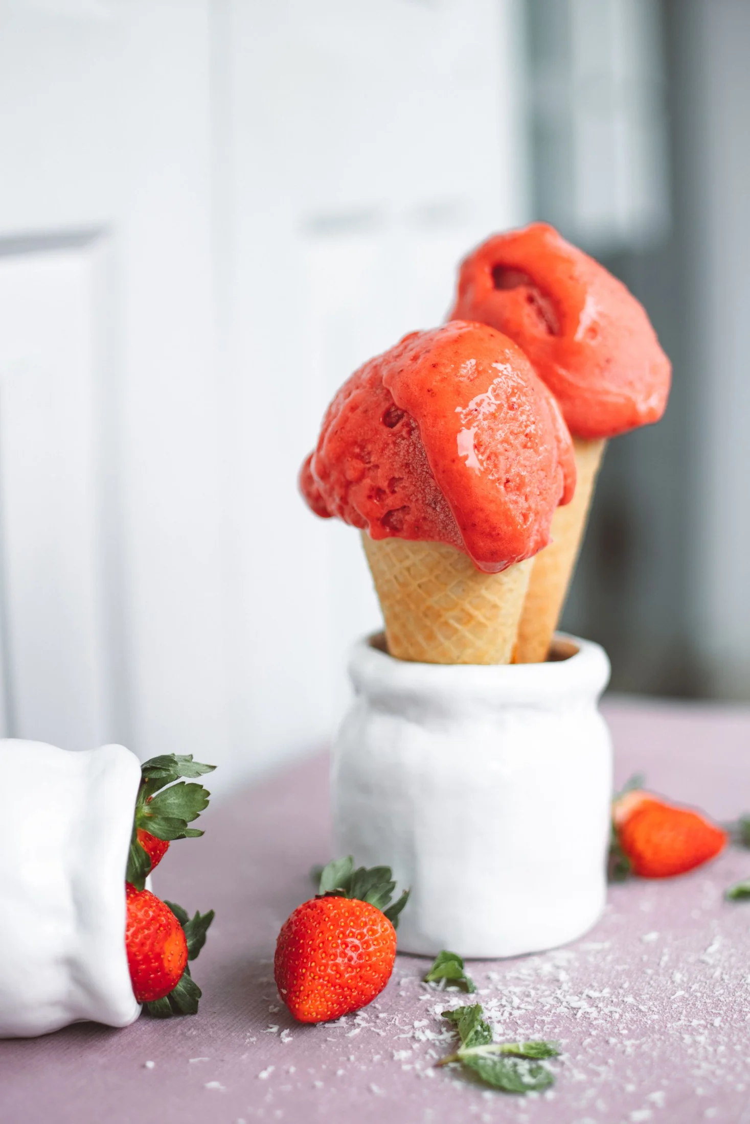 Two strawberry sorbet cones beside strawberries