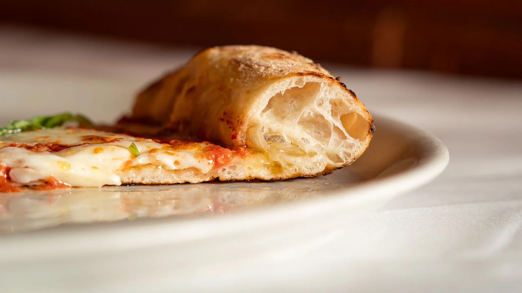 The airy golden crust of a pizza slice