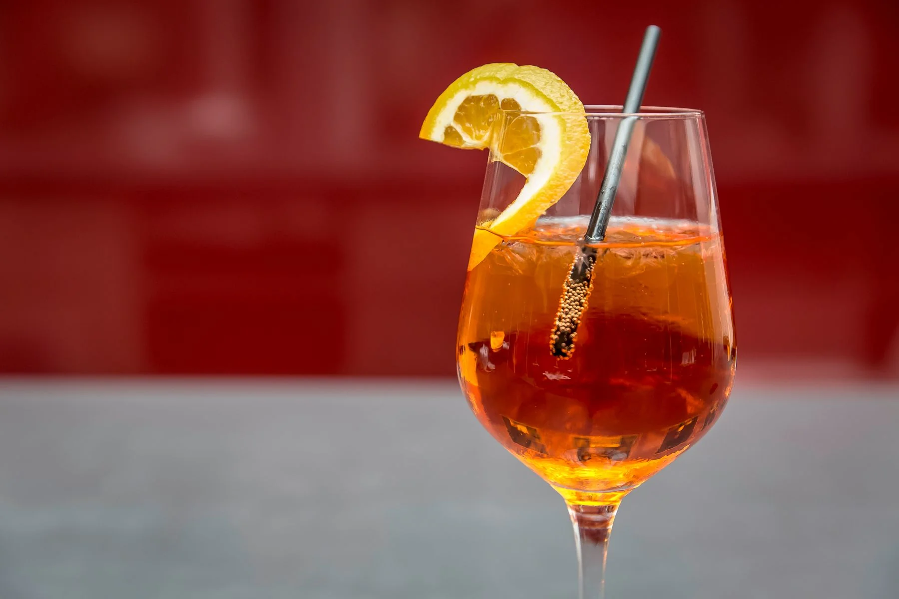 An orange sparkling drink with a lemon wedge