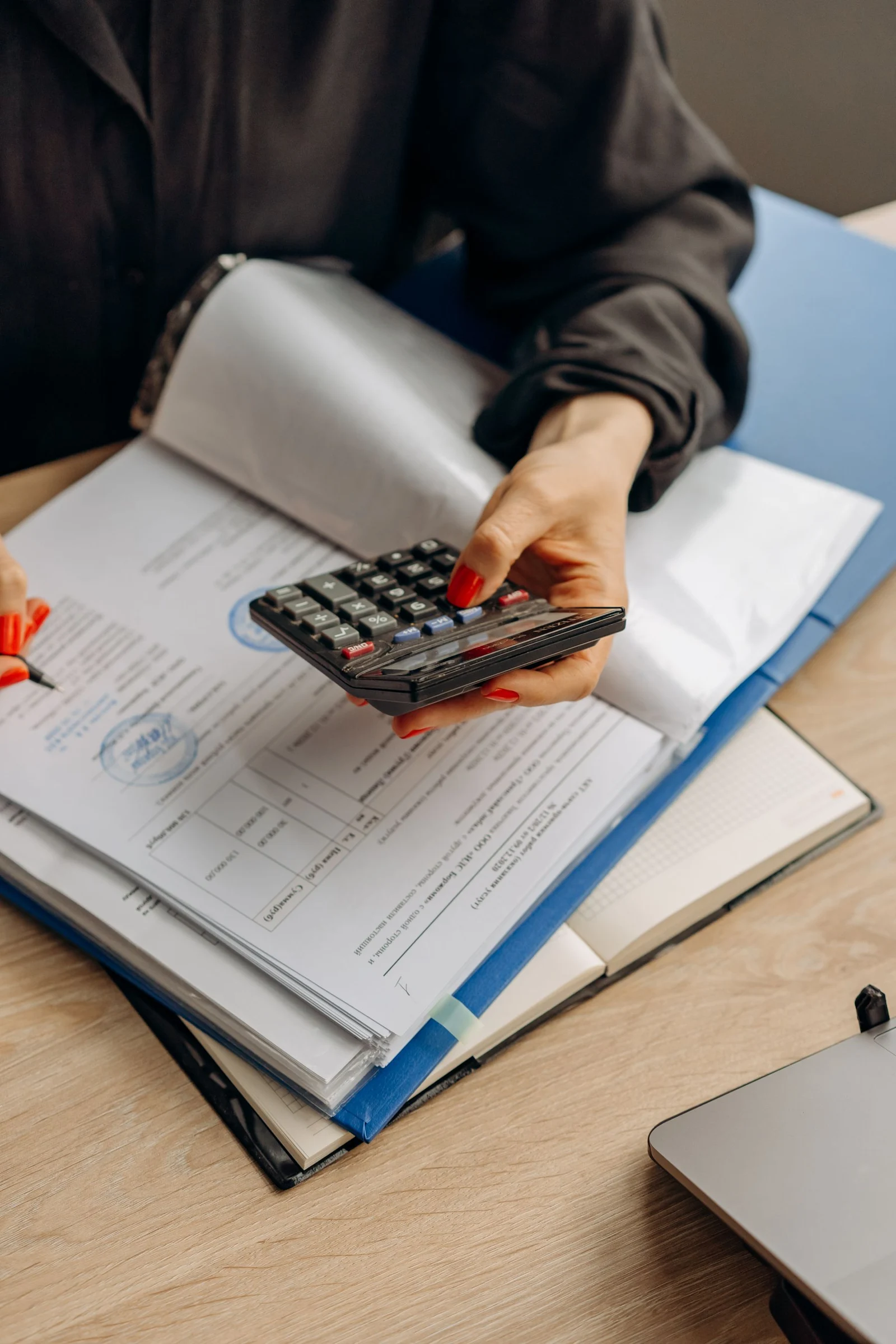 Hands checking documents with a calculator