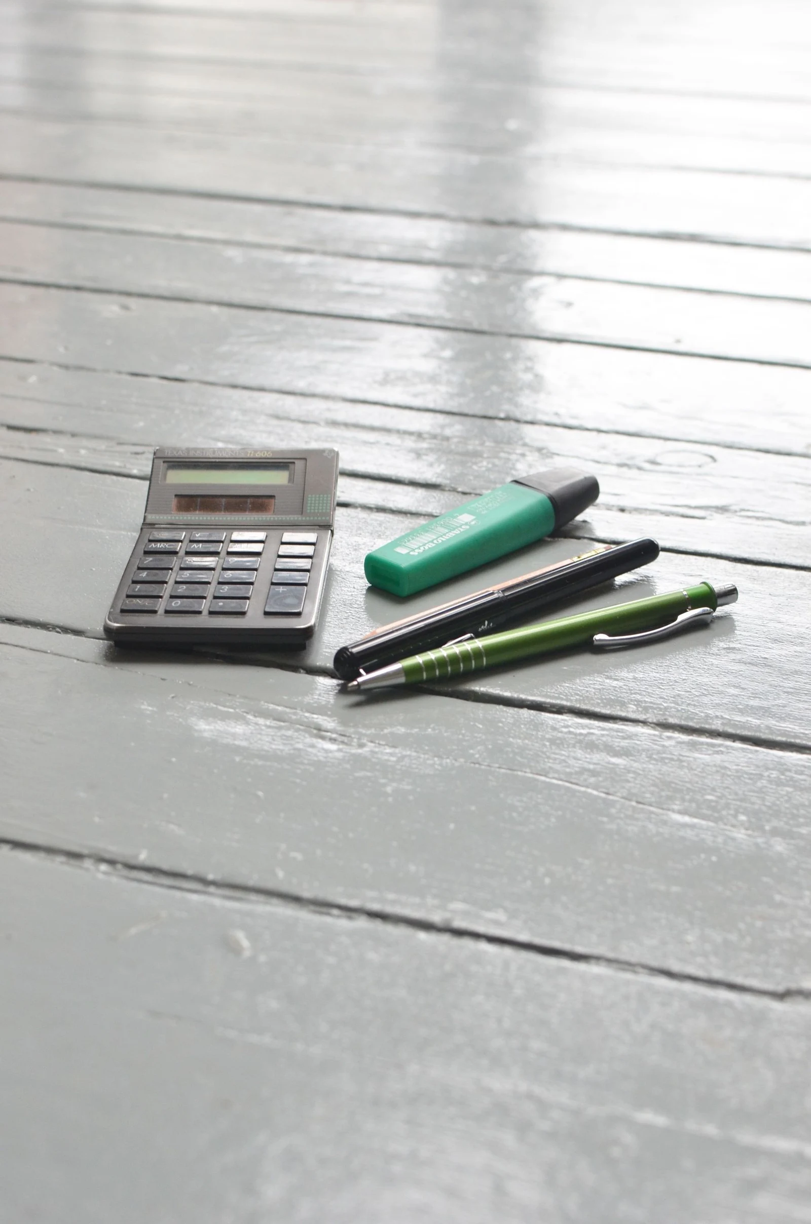 Calculator and stationery in sunlight on a white desk