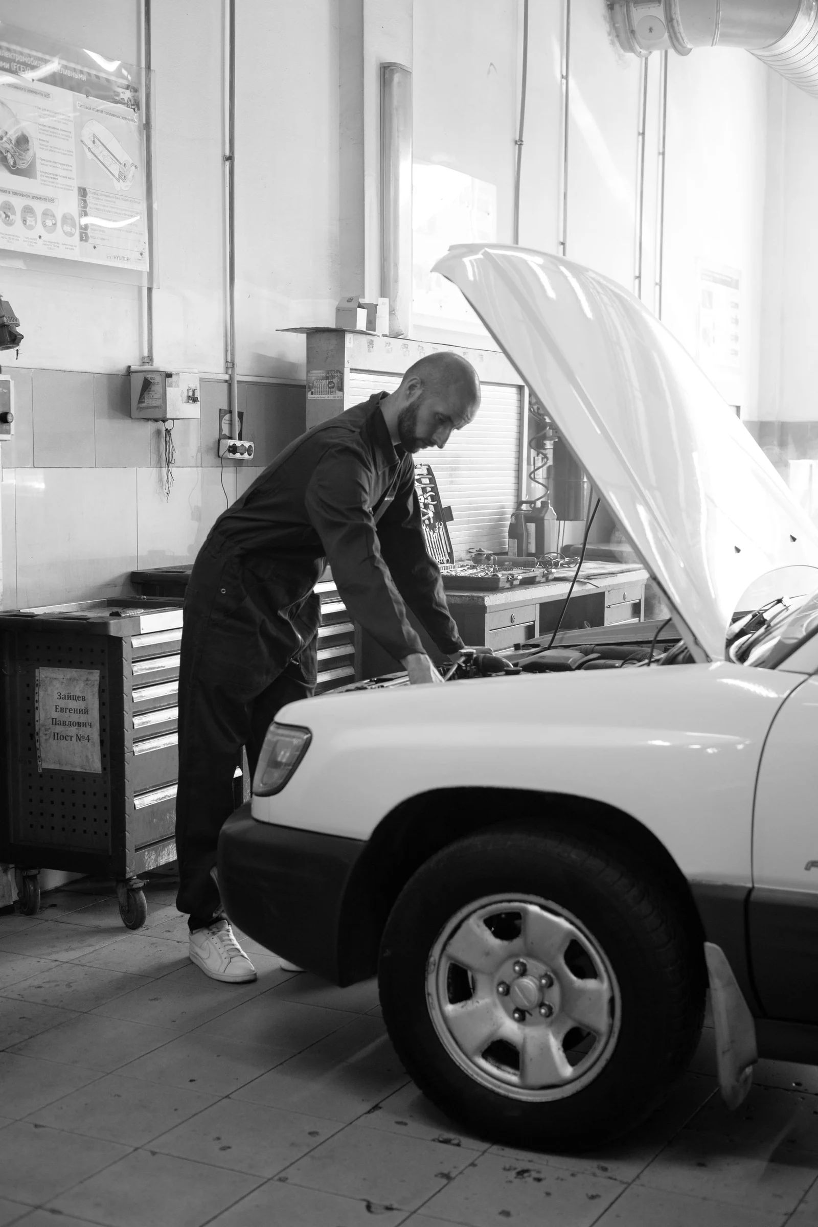 Mechanic inspecting a car in a light workshop