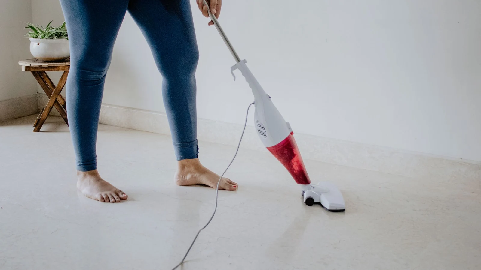 Person vacuuming a pale tiled floor in a home