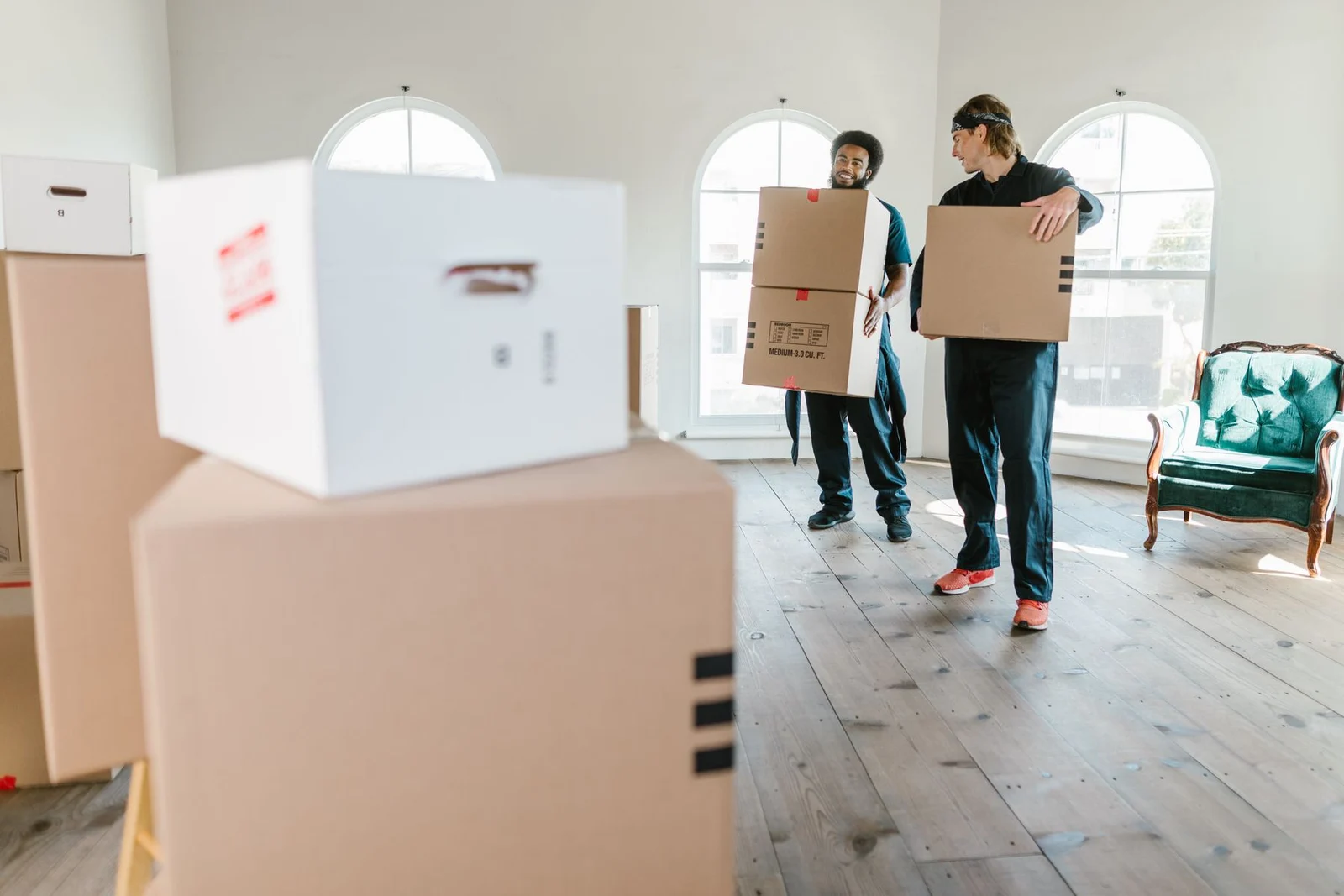 Two movers carrying cartons in a bright room