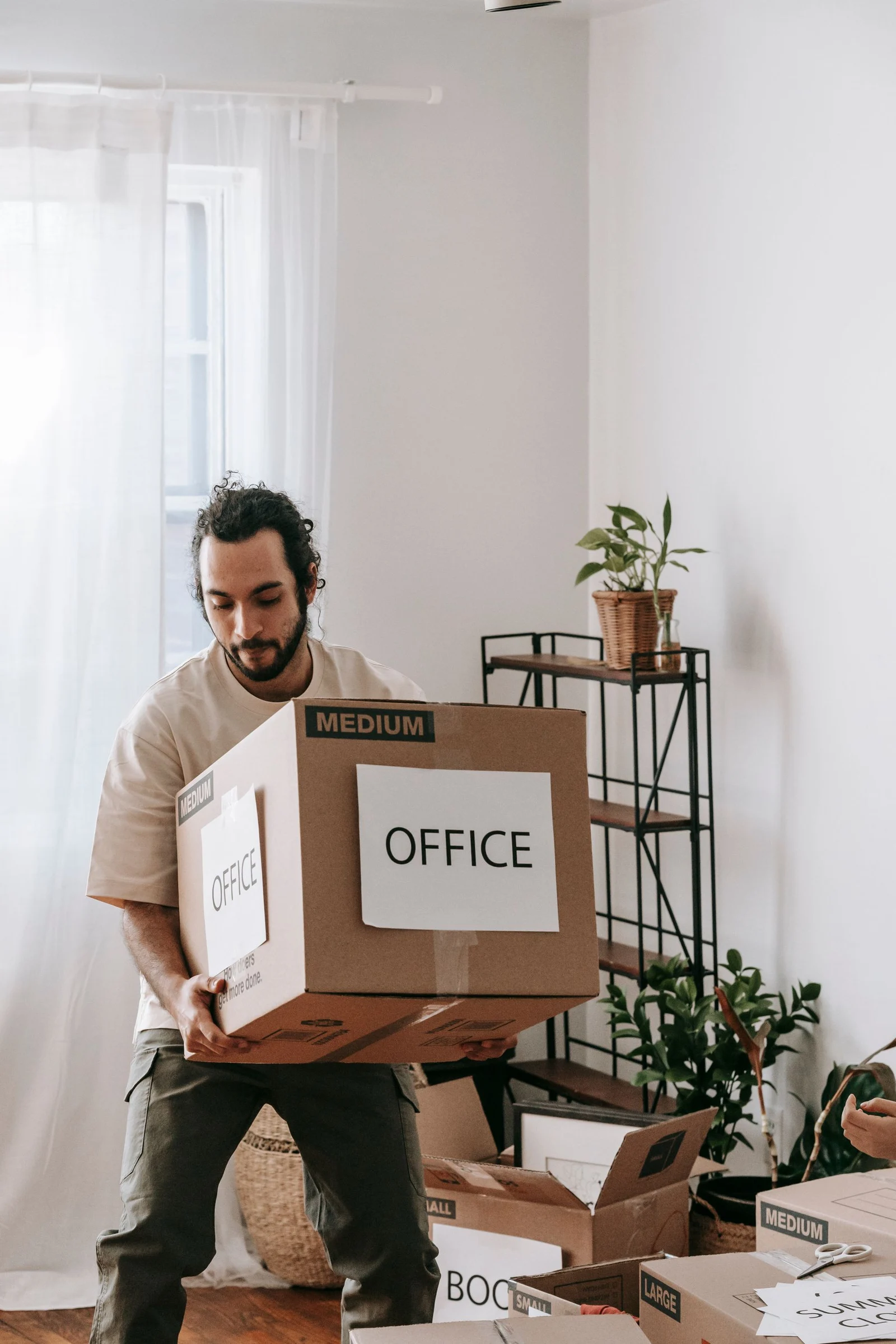 Person carrying a box marked office during a move