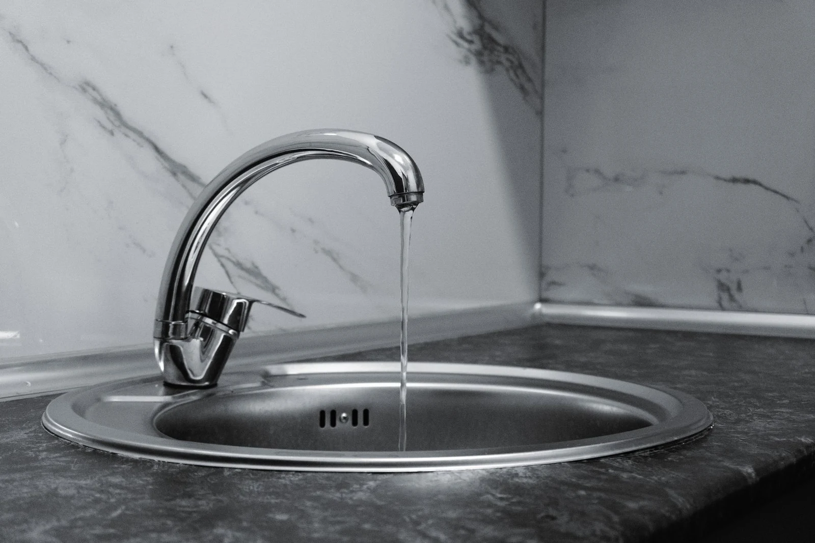 Chrome kitchen faucet with running water above a sink