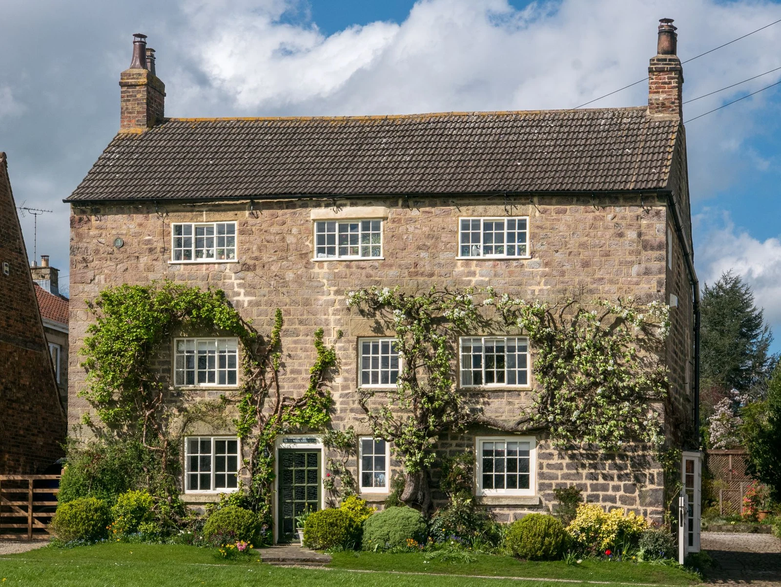 Stone countryside cottage with climbing plants and a garden