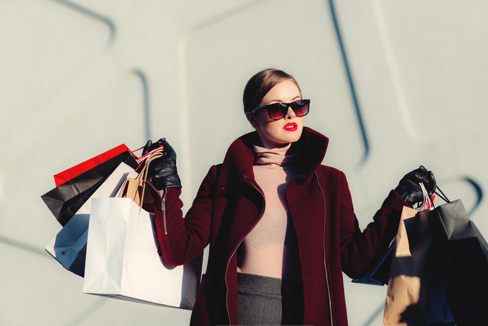 Fashion portrait in a burgundy coat with shopping bags
