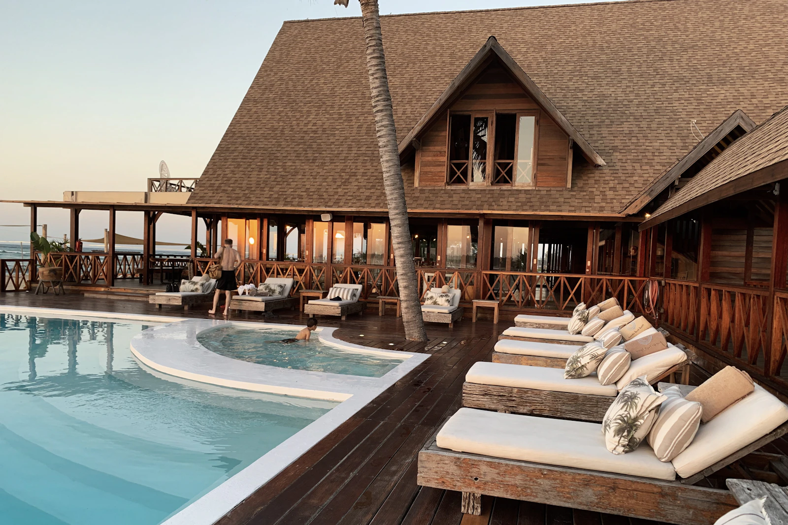 A hotel terrace and pool surrounded by palms